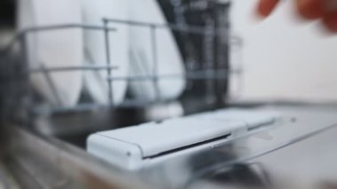 Bulaşık makinesine deterjan koyan adam..