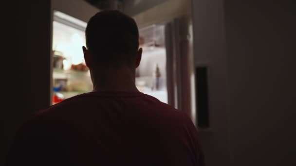 夜に冷蔵庫で食べ物を探している男 — ストック動画