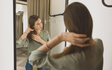 Giyim mağazasının soyunma odasında duran genç kız..