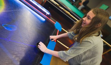 Genç kız eğlence merkezinde hokey oynuyor..