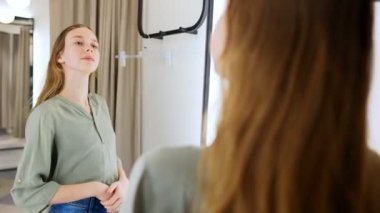 Giyim mağazasının soyunma odasında duran genç kız..