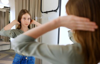 Giyim mağazasının soyunma odasında duran genç kız..