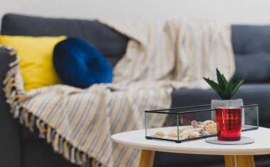 Battaniye ve yastıklı komodin ve kanepe..