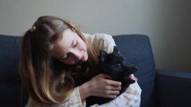 Genç kız evde köpek yavrusuyla oynuyor..
