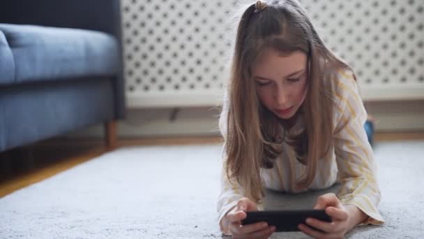 Zwillingsmädchen Mit Smartphone Auf Dem Teppich Liegend — Stockvideo