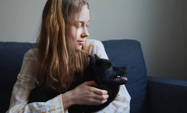 Tween girl playing with puppy at home.