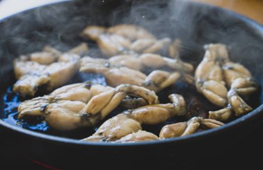 Geleneksel tavada kızarmış kurbağa bacağı pişirme.