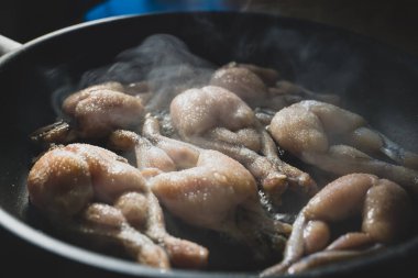 Geleneksel tavada kızarmış kurbağa bacağı pişirme.