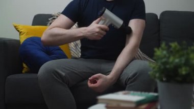 Evde masaj aleti ile masaj yapan bir adam..