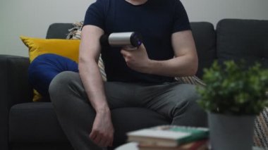 Evde masaj aleti ile masaj yapan bir adam..