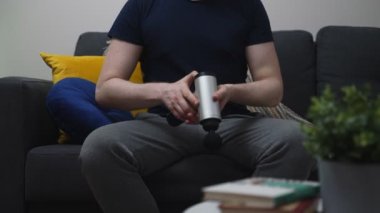 Evde masaj aleti olan bir adam göğsüne masaj yapıyor..