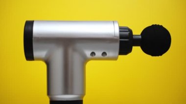 Sarı arka planda dönen masaj perküsyon cihazı. Reklam için uygun..