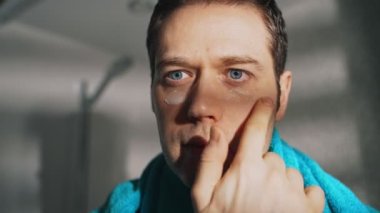 Adam banyoda yüzüne krem sürüyor..