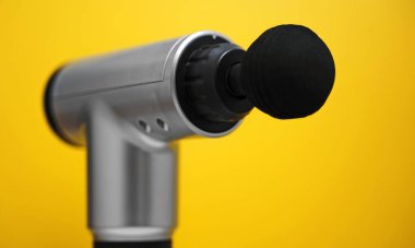 Sarı arka planda masaj perküsyon cihazı. Reklam için uygun..