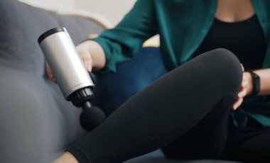 Evde masaj aletli masaj yapan bir kadın..