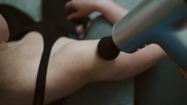 Evde masaj aleti olan bir erkek kadına masaj yapıyor..