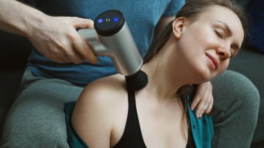 Evde masaj aleti olan bir erkek kadına masaj yapıyor..