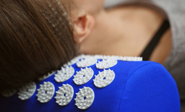 Woman is using acupuncture applicator pad for her neck.