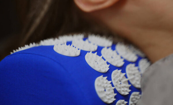 Woman is using acupuncture applicator pad for her neck.