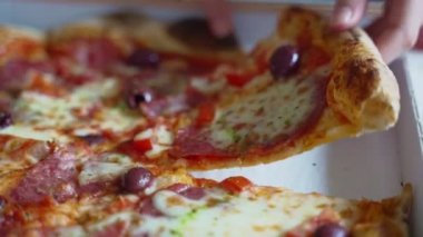 Çocuk eli pizza alır pepperonili ve zeytinli.