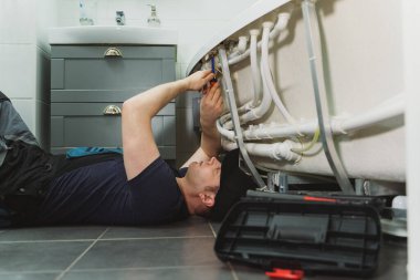 Adam banyo küvetinin boru sistemini hidromasaj ile kuruyor..