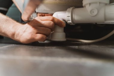 Tesisatçı plastik banyo tuzağını söküyor..