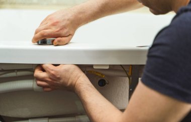 Adam banyo küvetinin boru sistemini hidromasaj ile kuruyor..