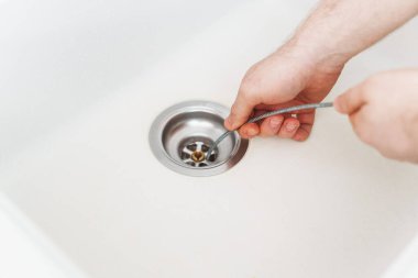 Tesisatçı lavaboyu açmak için drenaj yılanı kullanıyor..