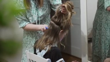 Anne evde saçını kestirmeden önce kızını tarıyor..