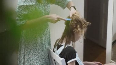 Anne evde saçını kestirmeden önce kızını tarıyor..