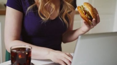 Kadın ve hamburger iş yerinde. Sonsuz acele kavramı.