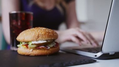 Kadın ve hamburger iş yerinde. Sonsuz acele kavramı.