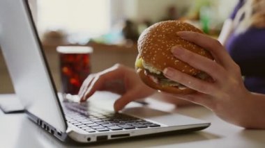 Kadın ve hamburger iş yerinde. Sonsuz acele kavramı.