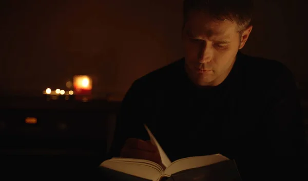 Handsome man reading book at night.