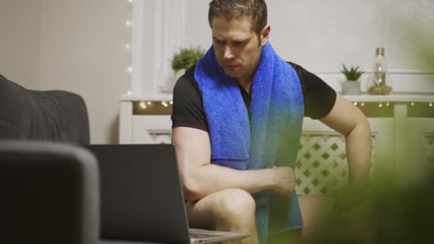 男はノートパソコンで運動を見ている 自宅でのスポーツ活動 — ストック動画