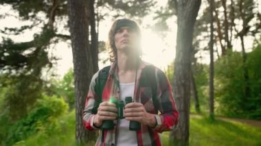 Ormanda sırt çantası ve dürbünlü bir adam var..