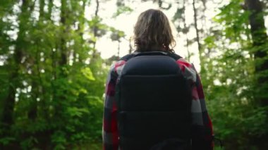 Ormanda sırt çantalı ve güneş gözlüklü bir adam. Yay atışı.