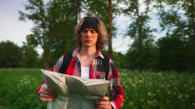 Ormanda haritalı ve sırt çantalı bir erkek turist.