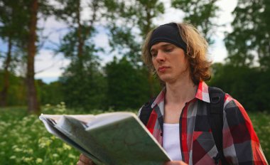 Ormanda haritalı ve sırt çantalı bir erkek turist.