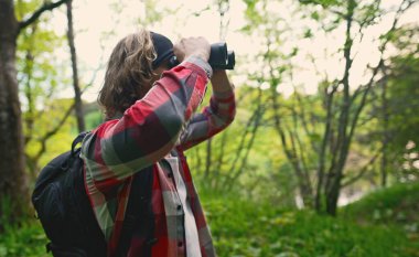 Ormanda sırt çantası ve dürbünlü bir adam var..