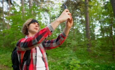 Ormanda akıllı telefonla selfie çeken bir adam..