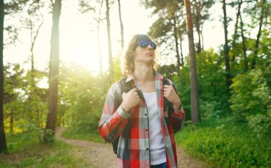 Ormanda sırt çantalı ve güneş gözlüklü bir adam. Yay atışı.