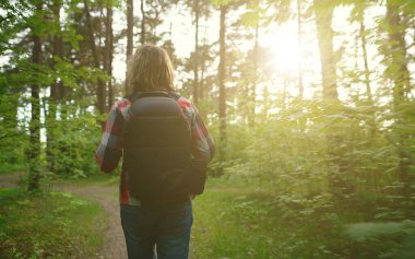 Ormanda sırt çantalı ve güneş gözlüklü bir adam. Yay atışı.
