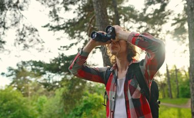 Ormanda sırt çantası ve dürbünlü bir adam var..