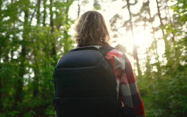 一个背着背包和太阳镜在树林里的男人弧形射击 — 图库照片