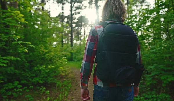 一个背着背包和太阳镜在树林里的男人弧形射击 — 图库照片