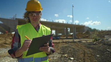 Yol kavşağı inşaat sahasında belgeleri olan inşaat mühendisi..