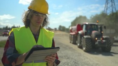 Yol kavşağı inşaat sahasında tablet bilgisayarı olan bir inşaatçı.