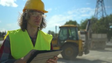 Yol kavşağı inşaat sahasında tablet bilgisayarı olan bir inşaatçı.