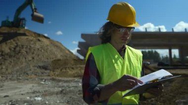 Yol kavşağı inşaat sahasında belgeleri olan inşaat mühendisi..